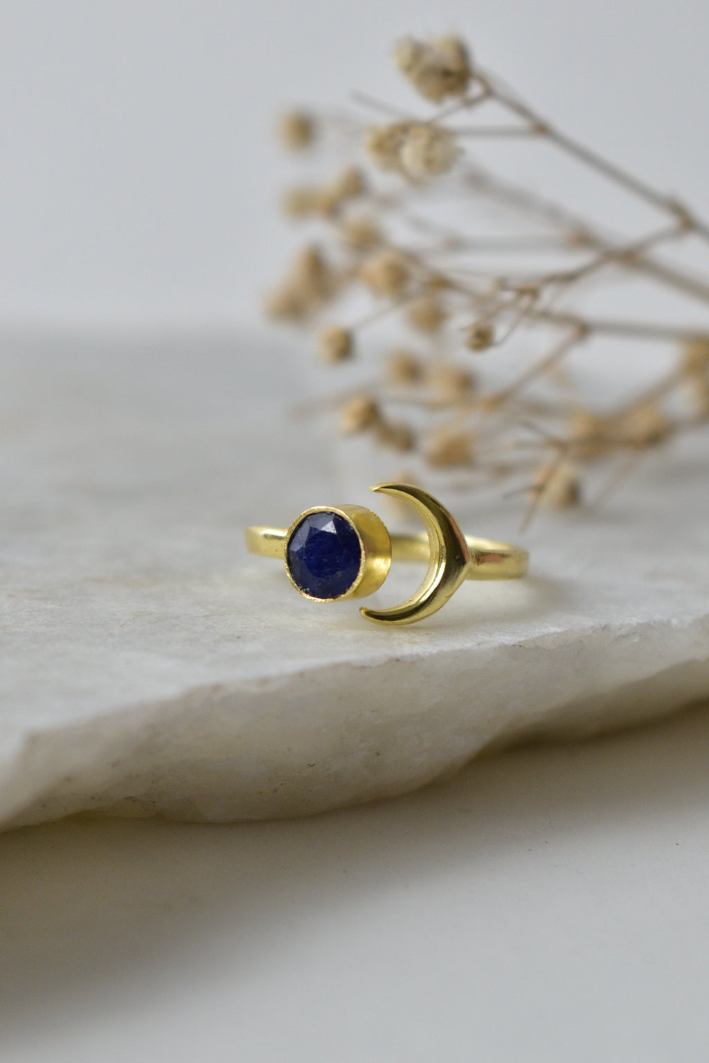 Gold ring with a blue gemstone on a white fabric background