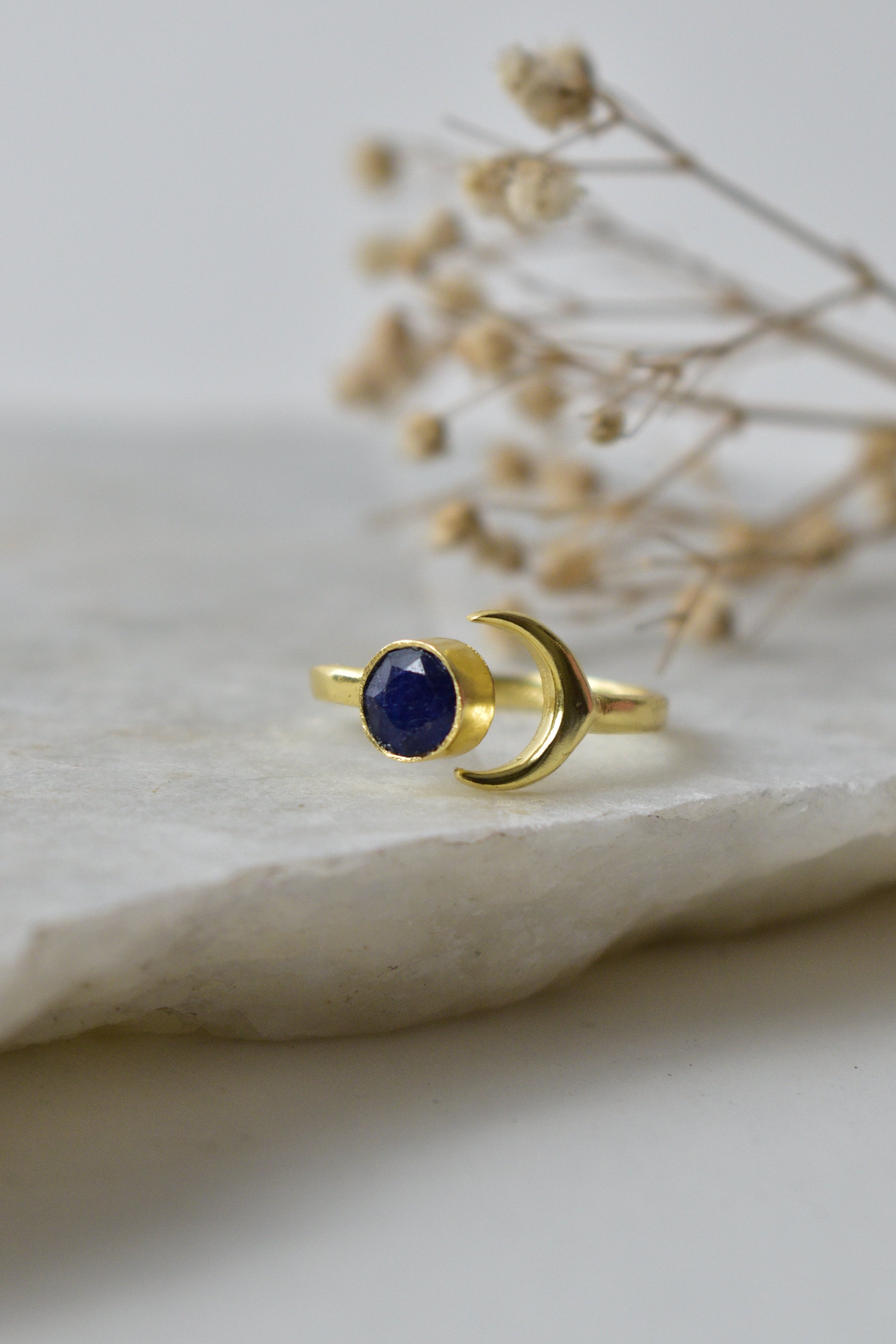 Gold ring with a blue gemstone on a white fabric background