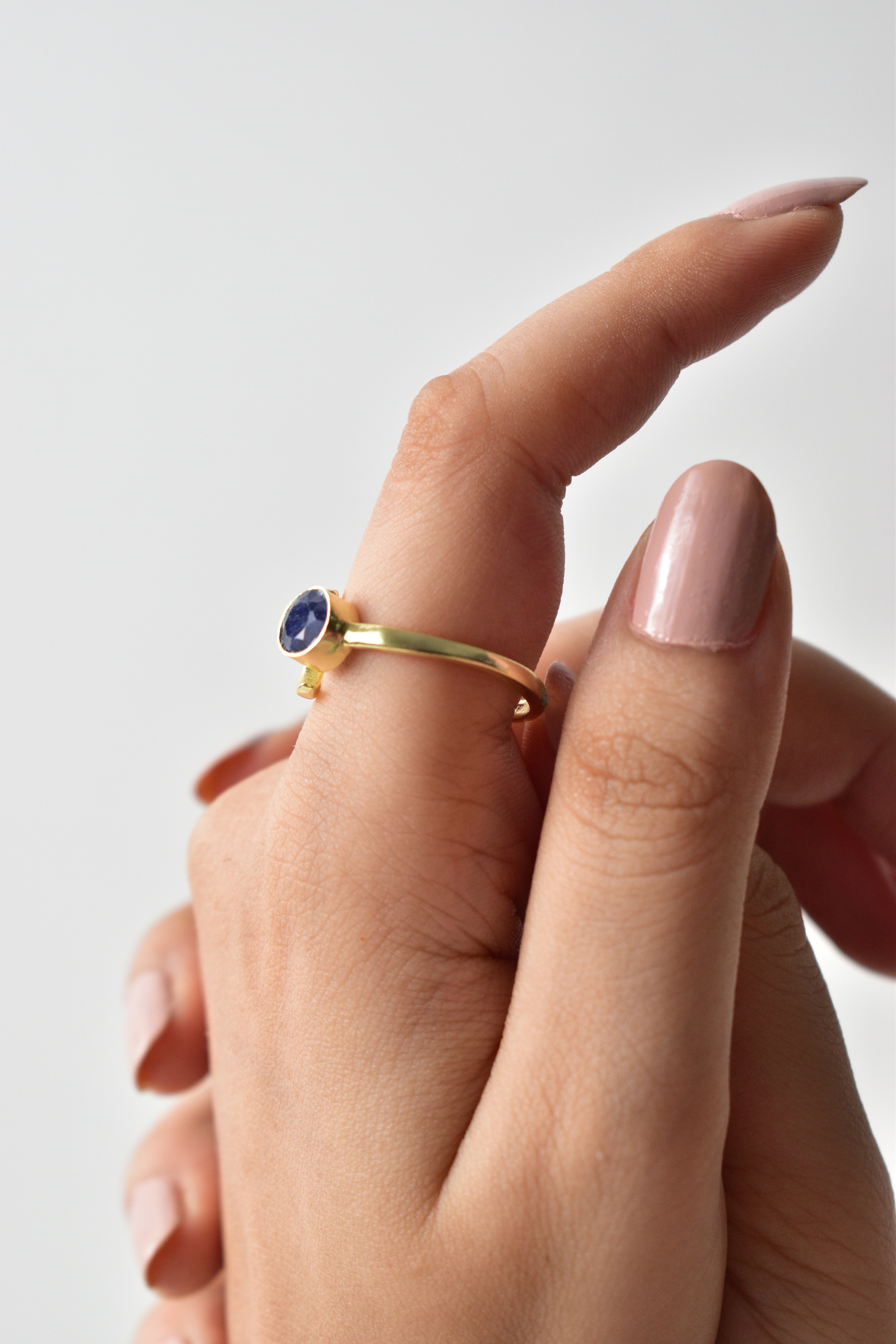 Gold ring with a blue gemstone on a light gray background