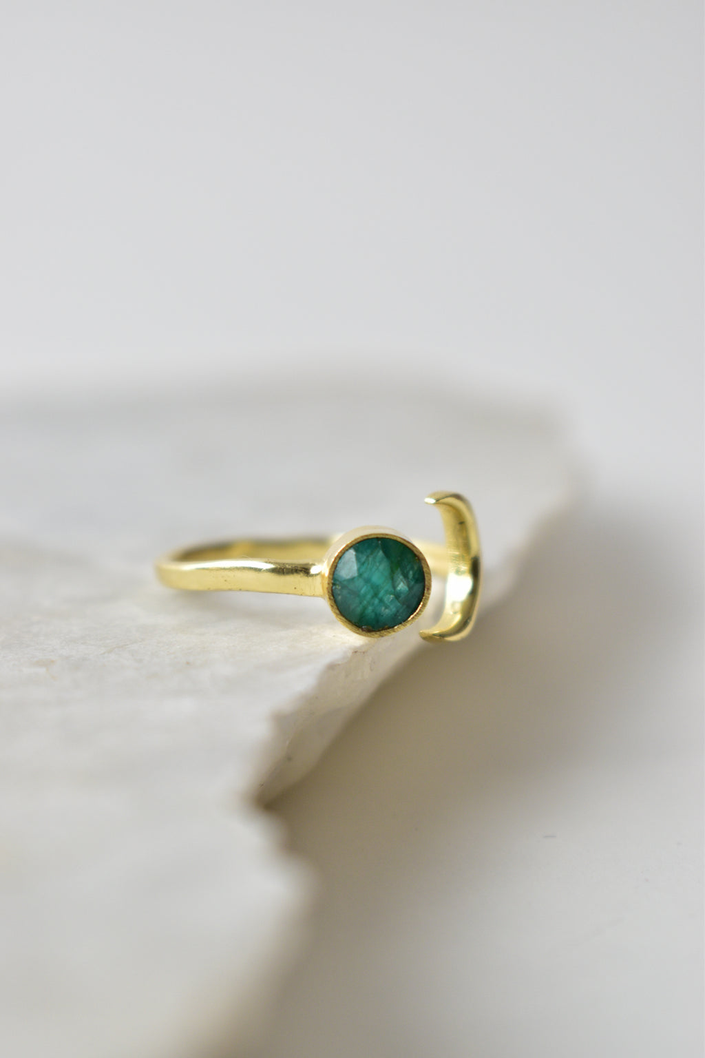 Gold ring with a green gemstone on a white background