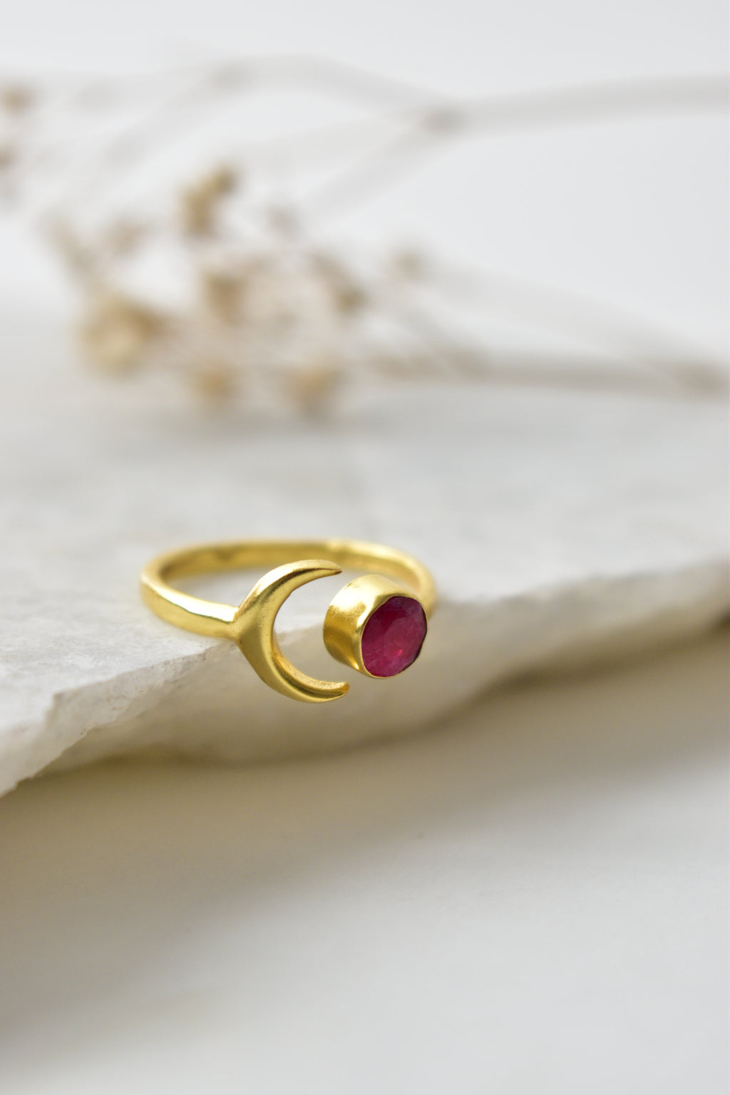 Gold ring with a red gemstone on a white background