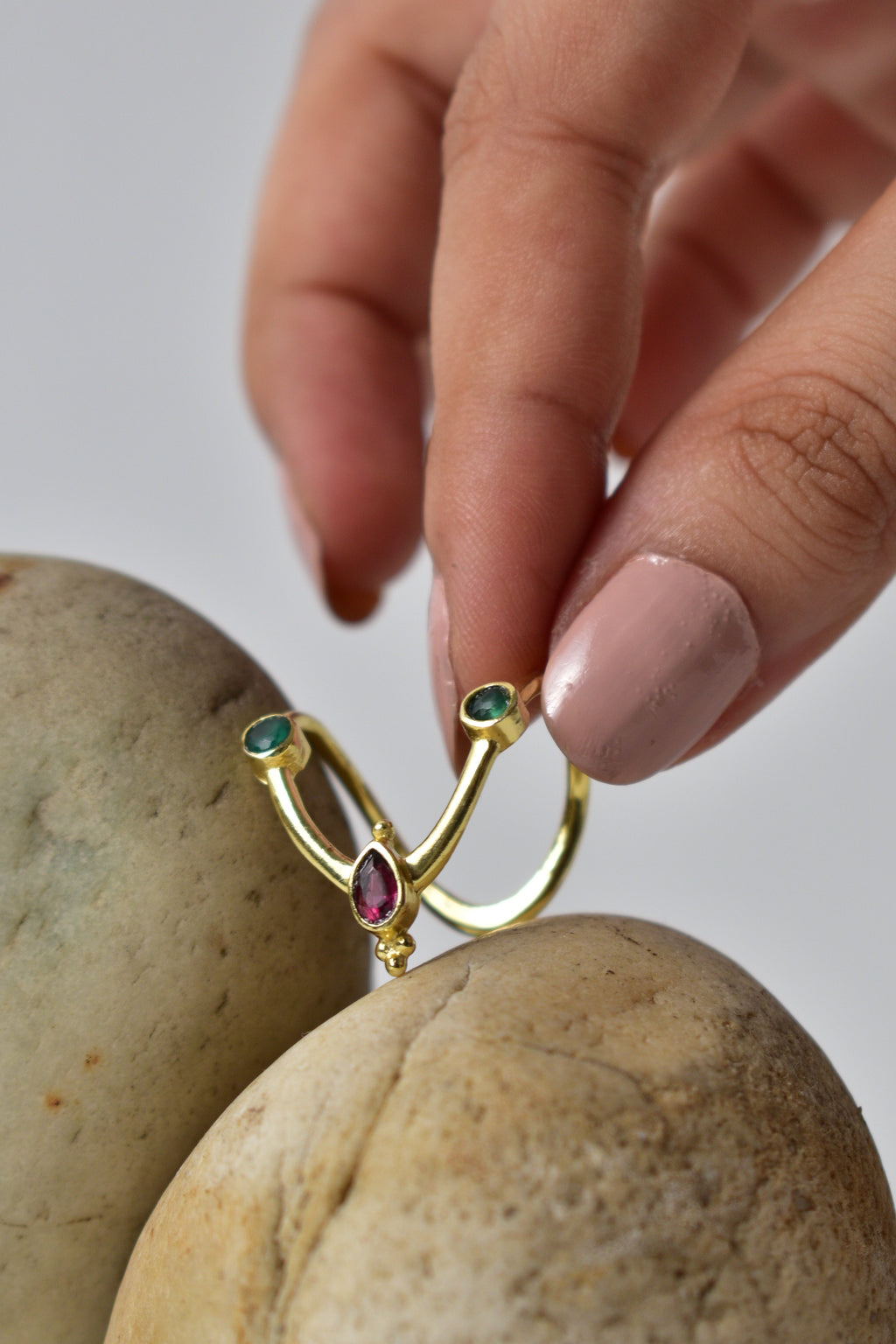 Gold ring with gemstones held between two potatoes against a neutral background