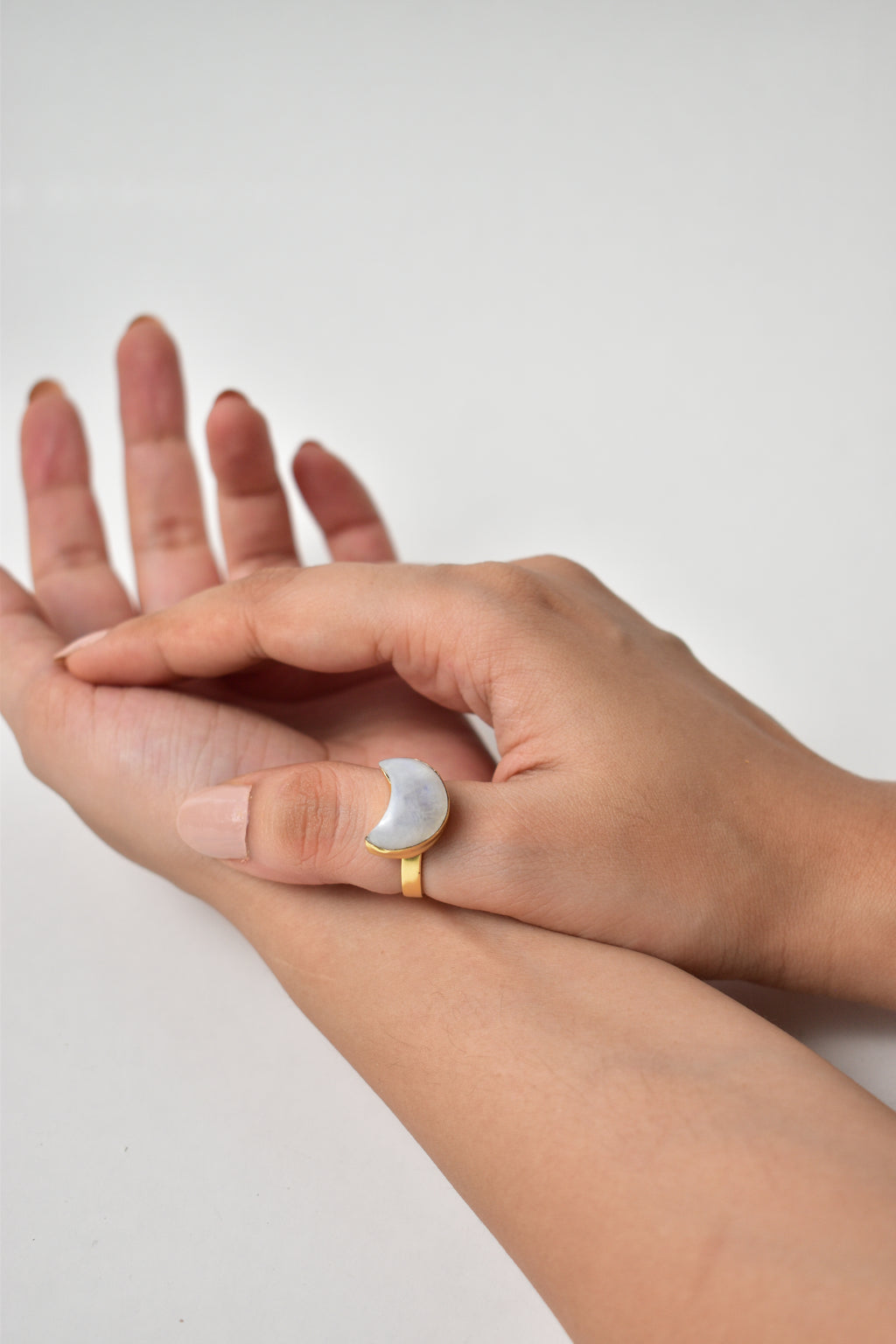 Close-up of a hand wearing a gold ring on a light background