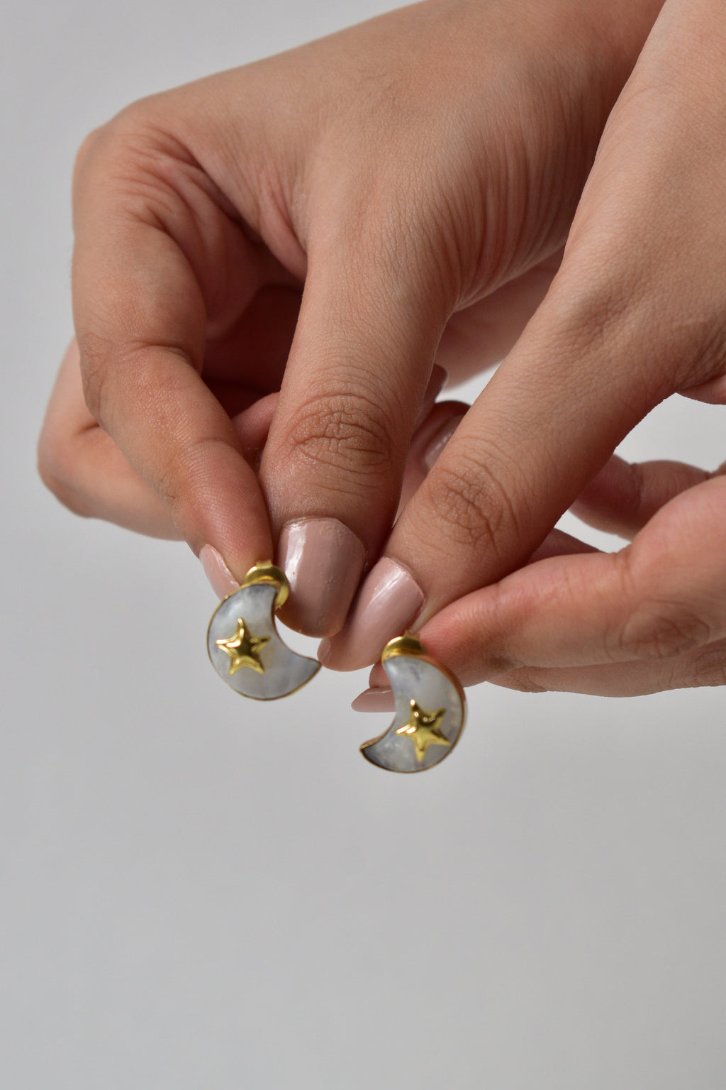 Close-up of hands holding a small decorative item against a plain background