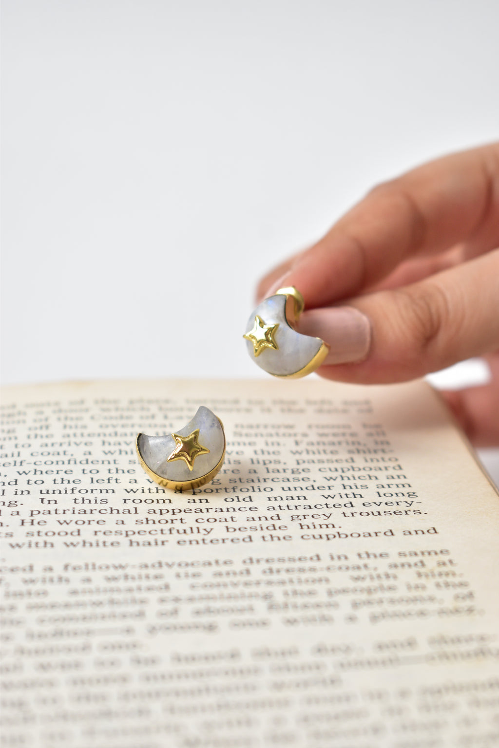 Star and moon earrings held above a book