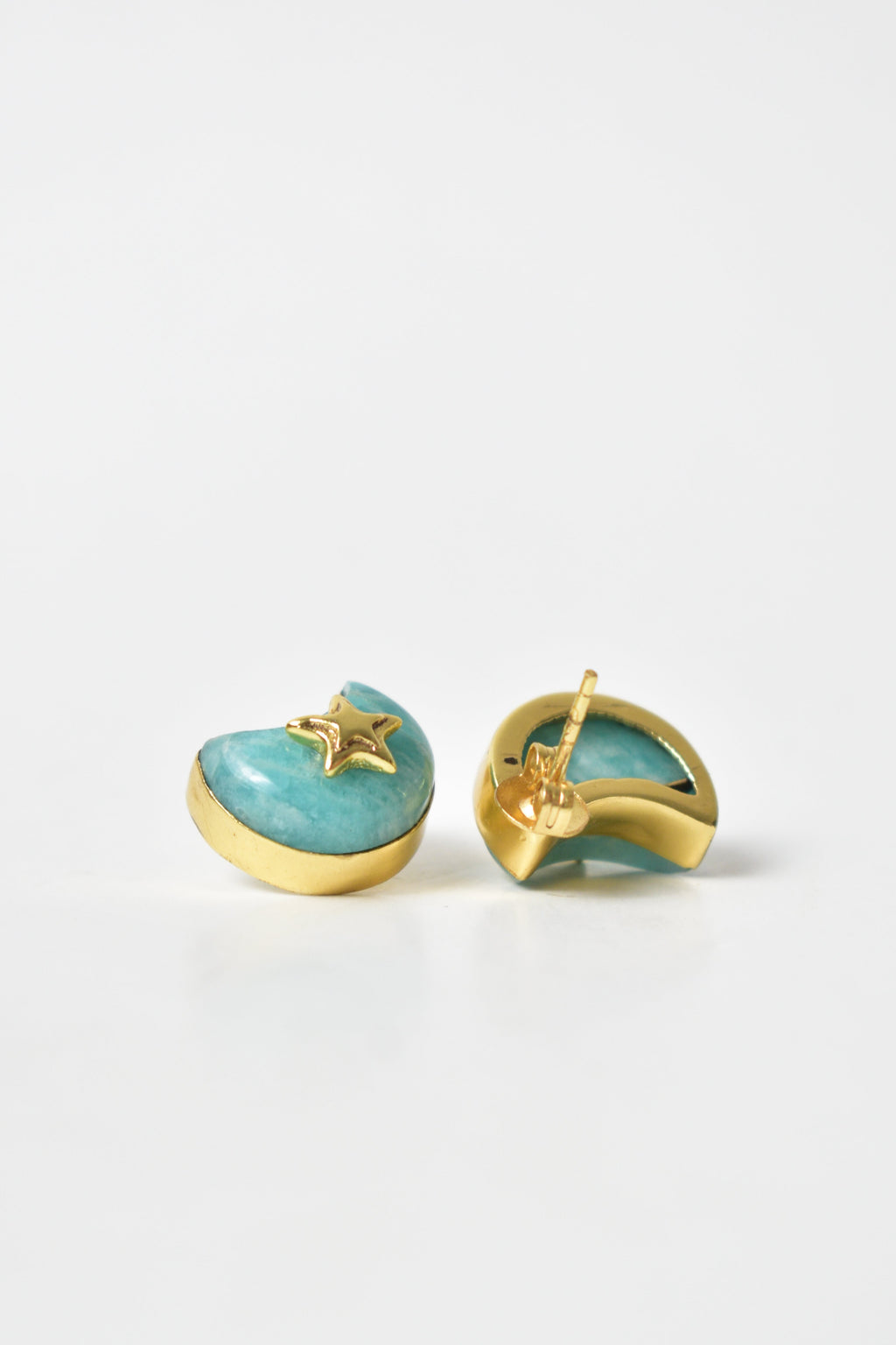 Pair of earrings with gold and turquoise design on a light gray background