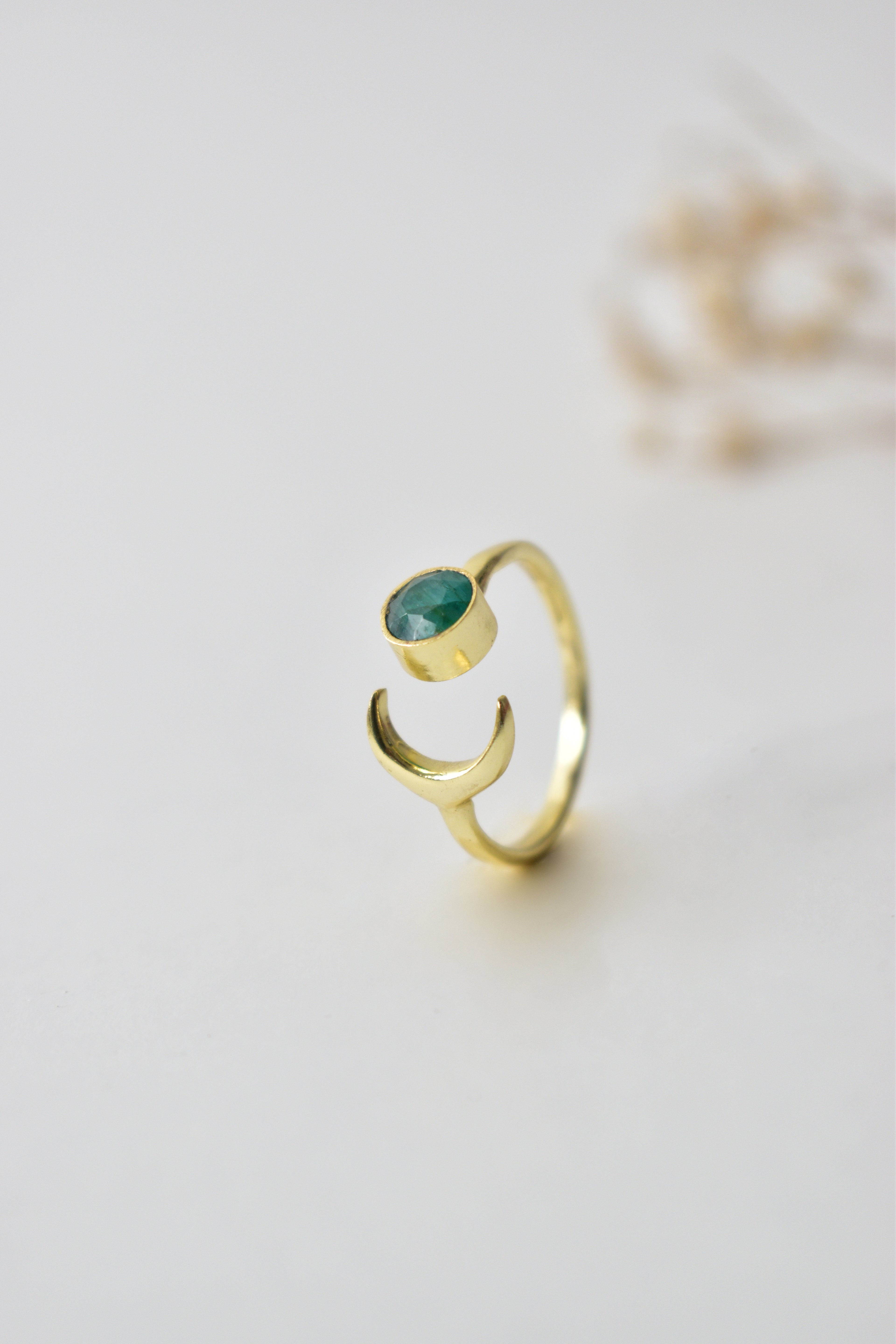 Gold ring with a green gemstone on a light background