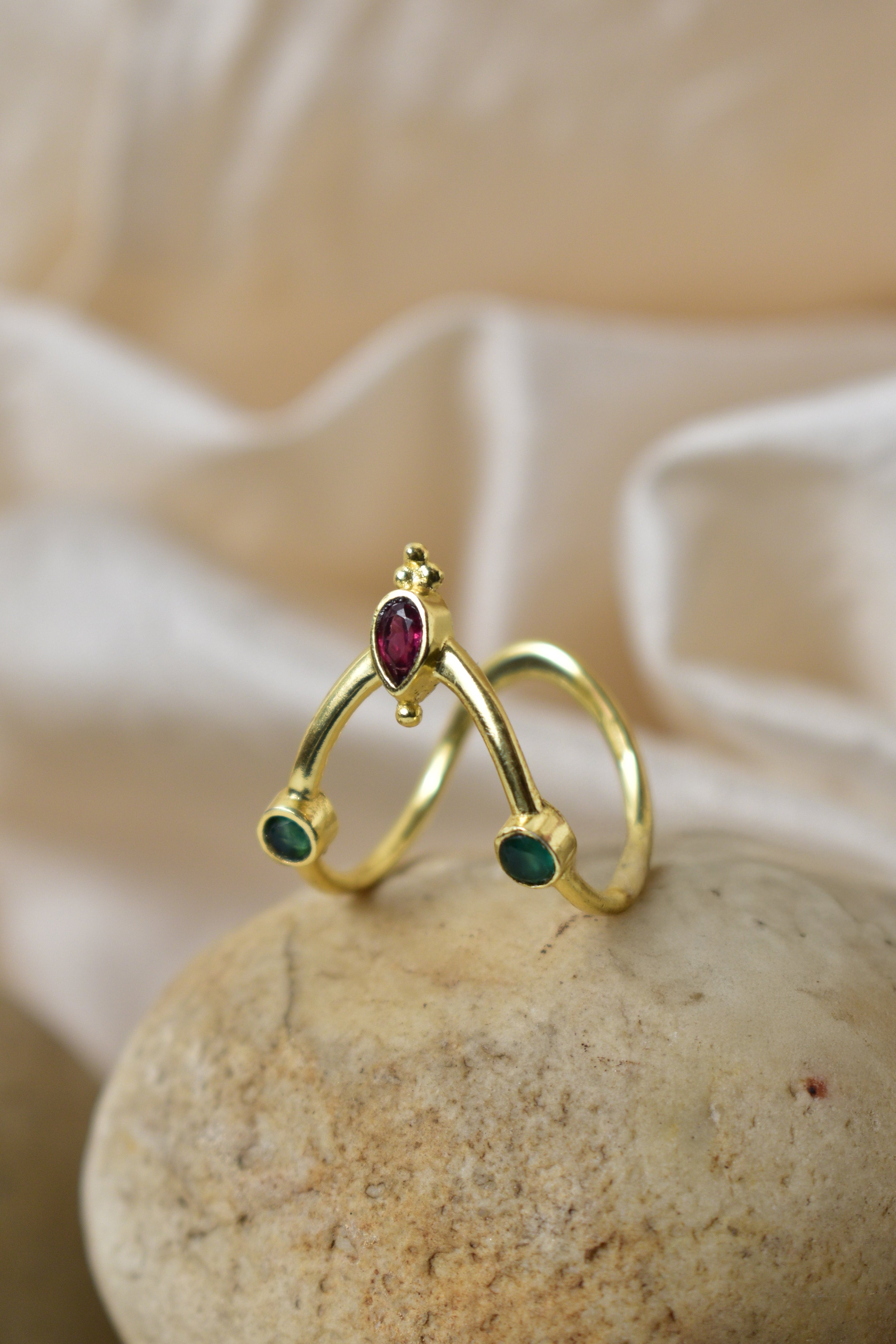 Gold ring with gemstones on a stone surface with a soft beige background