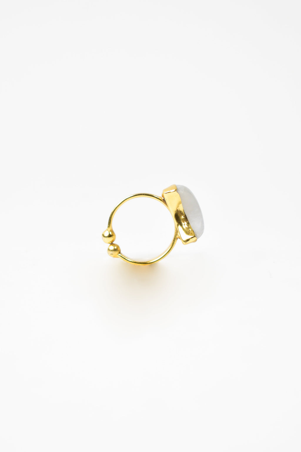 Gold ring with a white stone on a light beige background