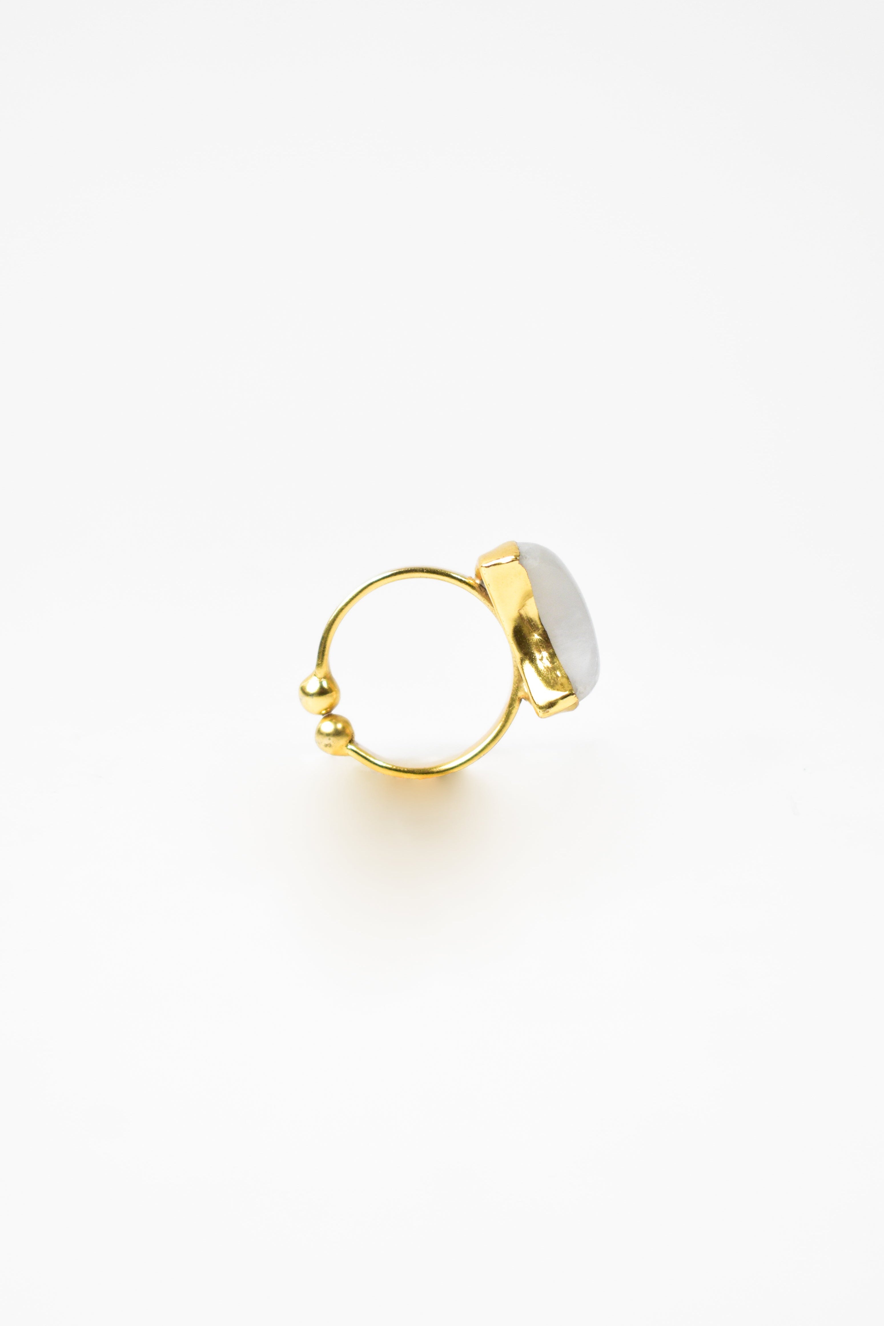 Gold ring with a white stone on a light beige background